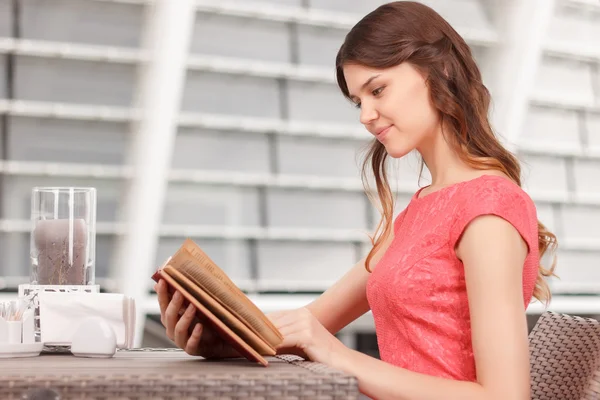 Pretty young woman reading in cafe — Stock Photo, Image
