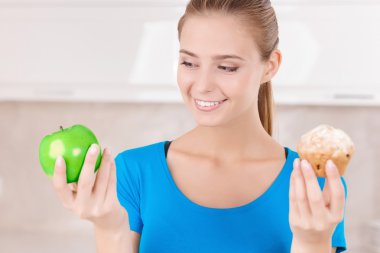 Nice girl holding apple and muffin 