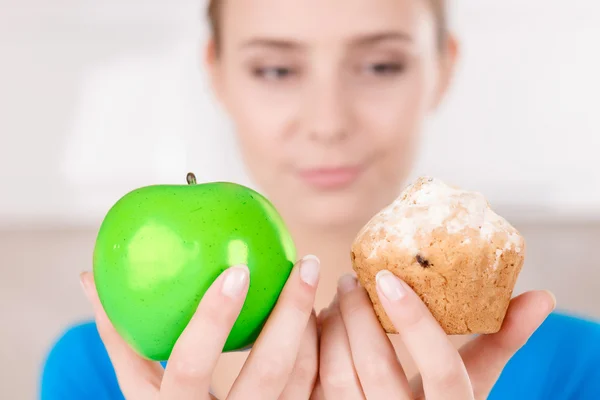 Nice girl holding apple and muffin — Stockfoto