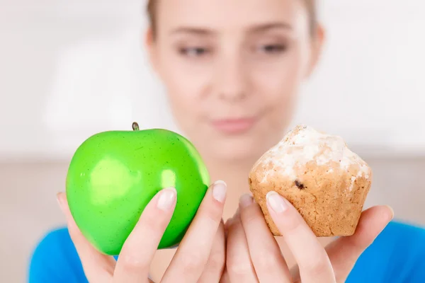 Menina agradável segurando maçã e muffin — Fotografia de Stock