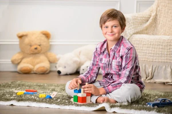 Веселый мальчик играет на ковре — стоковое фото