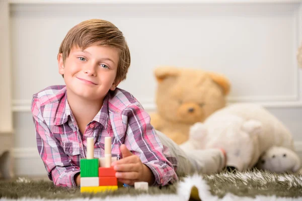 Ragazzo allegro che gioca sul tappeto — Foto Stock