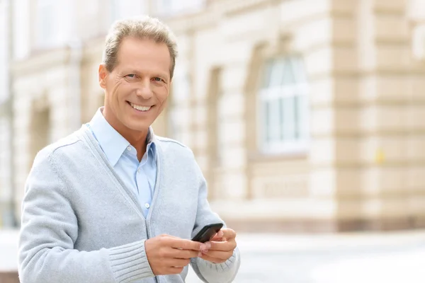 Χαμογελαστός άνθρωπος κρατώντας το κινητό τηλέφωνο — Φωτογραφία Αρχείου