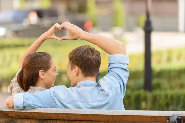 Joli jeune couple assis sur le banc — Photo