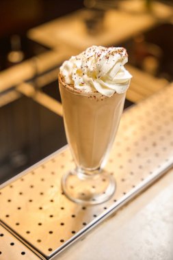 Köpüklü, kremalı bir içeceğe yakın plan. Üstünde de bar tezgahında bol miktarda krema var.