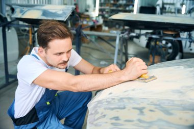 Otomobil tamirhanesinde güç tampon makinesiyle araba cilalayan erkek işçi. Araba konseptinin tamiri