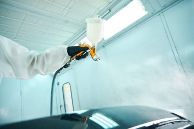 Koruyucu takım elbiseli otomobil boyacısının odaları boyamasını kapatın. Araba servisi konsepti