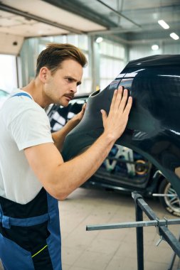 Benzin istasyonunda çalışan üniformalı genç bir tamirci. Araba servisi konseptini boyamak. Araba temizleme