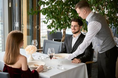 Garson masaya servis yapıyor. Lokantada birbirini seven erkek ve kadın birbirlerine bakıyor. Romantizm, tarih, ilişki kavramı