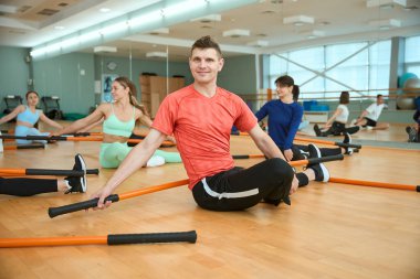 Eğitimdeyken spor sopalarıyla yerde oturan pozitif erkek ve kadınlar. Fitness, spor, eğitim, spor salonu ve yaşam tarzı konsepti