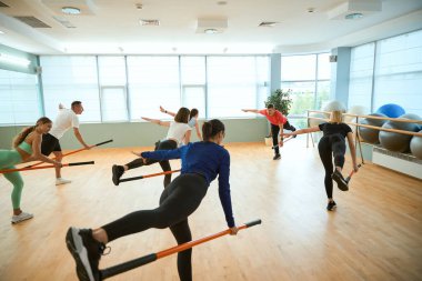 Spor salonunda jimnastik çubukları kullanarak denge kuran bir grup insanı gösteren bir erkek antrenör. Fitness, spor, eğitim, spor salonu ve yaşam tarzı konsepti