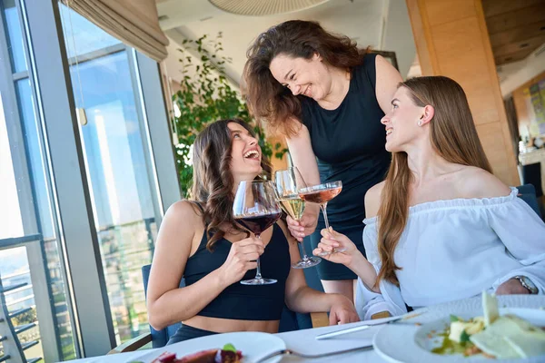 Gülümseyen genç kızlar kadehlerini kaldırırken kahkahalar atıyorlar, kafede konuşuyorlar.