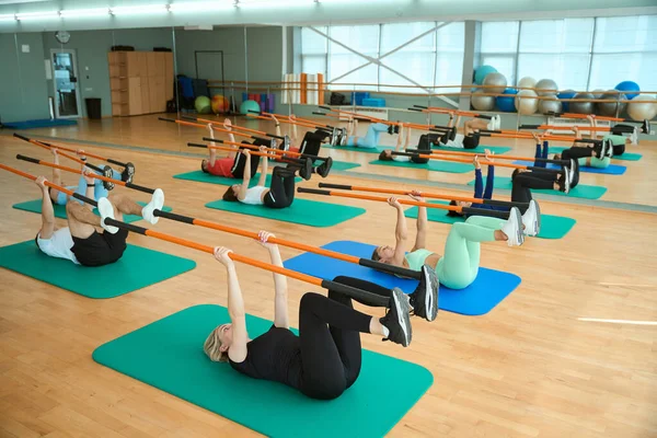Spor salonunda jimnastik sopasıyla antreman yapan bir grup insan. Fitness, spor, eğitim, spor salonu ve yaşam tarzı konsepti