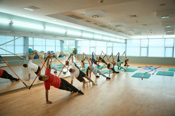 Beden eğitiminde jimnastik çubukları kullanarak sıralanmış sıralanmış gülümseyen sporcu insanlar fiziksel egzersizler yapıyorlar. Fitness, spor, eğitim, spor salonu ve yaşam tarzı konsepti