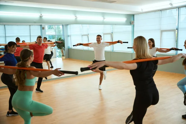 Beden eğitimi dersinde jimnastik çubukları kullanarak daire şeklinde ayakta duran bir grup insan. Fitness, spor, eğitim, spor salonu ve yaşam tarzı konsepti