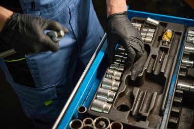 Mavi üniformalı yetişkin işçi atölyedeki alet çekmecesine anahtar koyuyor.