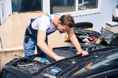 Garajda arabanın motoru üzerinde çalışan tamirci kaputu açık. Araba tamir hizmeti kavramı