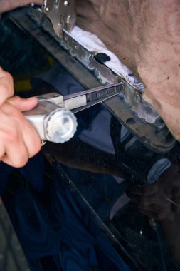 Tamirci, oto servis atölyesinde araba tamir için özel bir aletle çalışıyor. Araba tamir hizmeti kavramı