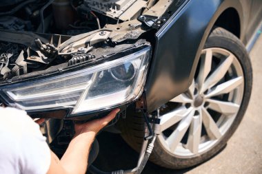 Bir atölyede yeni bir araba farıyla tamirciyi kapat. Araba tamir hizmeti kavramı