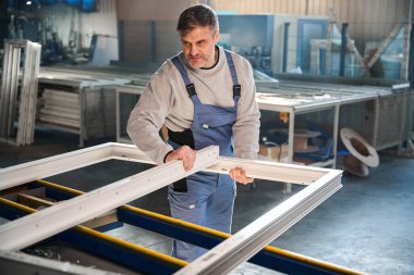 Fabrika ortamında PVC kapı ve pencere yapımında usta bir işçi.