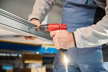 Tanımlanamayan profesyonel işçi fabrikadaki PVC kapı ve pencereleri birleştiriyor.