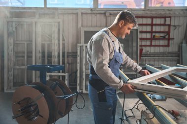 Fabrikadaki PVC kapı ve pencere montajında çalışan uzman bir erkek.