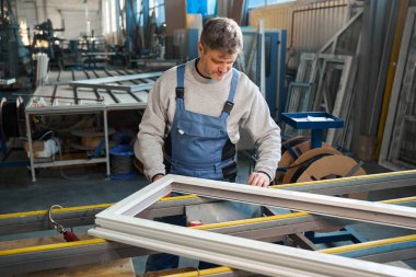 Erkek işçi alüminyum ve PVC pencere üretimi fabrikasında çalışıyor.