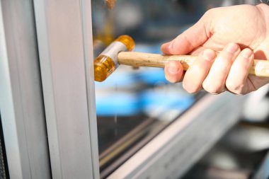 Tanımlanamayan profesyonel tamirci fabrikada boncukları cilalamak için PVC pencere inşaatı için araç kullanıyor