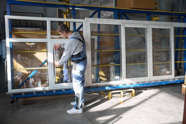 Fabrikada PVC pencere inşaatı için araç kullanan profesyonel bir tamirci