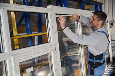 Erkek işçi alüminyum ve PVC pencere üretimi fabrikasında çalışıyor.