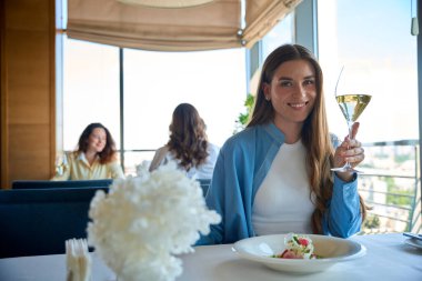Şampanyalı bir restoranda yemek yiyen mutlu genç bayan.
