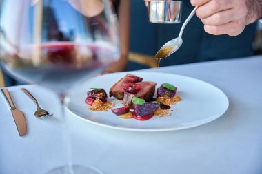 Garsonun, kadın için beyaz bir tabakta sosla güzelce dekore ettiği...