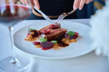 Restoranda soslu biftek yiyen genç bir bayan.