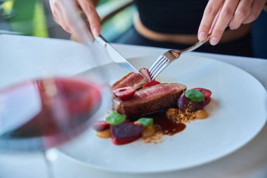 Restoranda biftek ve böğürtlen sosu yiyen bir kadının kesilmiş fotoğrafı.