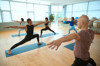 Grup fitness sınıfında kollarını açmış yoga pozisyonunda poz veren insanlar. Sağlıklı yaşam tarzı, spor, jimnastik, yoga stüdyosu