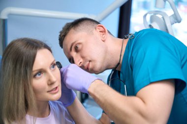 Genç bayan hastaların kulaklarını muayene eden erkek bir otolarolog. Otolaryngology konsepti