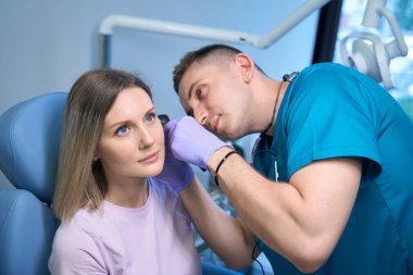 Tıp merkezindeki bir ses bilimciyle kulak kontrolü sırasında genç bir kadın. Otolaryngology konsepti