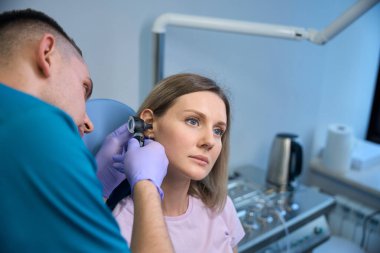 Erkek otolarolog klinikteki kadın hastayı muayene ediyor. Duyma bozukluğu. Otolaryngology konsepti