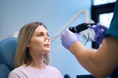 Kulak farlı KBB erkek doktoru otolaringolojist, burnu olan kadın hastayı tedavi ediyor. Otolaryngology konsepti