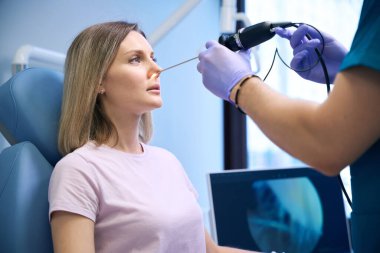 KBB doktoru, klinikte kadın hasta burnunun endoskopi prosedürünü gerçekleştirir. Otolaryngology konsepti