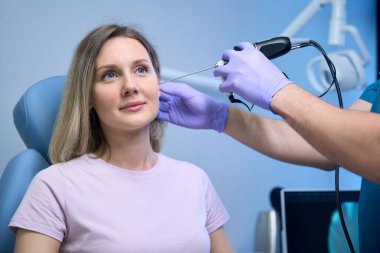 KBB erkek doktoru otolaringolojist. Kulak farları klinikte genç bir kadının kulaklarını tedavi ediyor. Otolaryngology konsepti