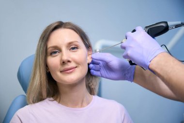 Tıp merkezindeki genç bayanın kulaklarını tedavi eden bir kulak farlı KBB doktoru. Otolaryngology konsepti