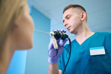 Erkek otolarolog elinde profesyonel bir cihaz tutuyor, kadın için endoskopi prosedürü uyguluyor. Otolaryngology konsepti