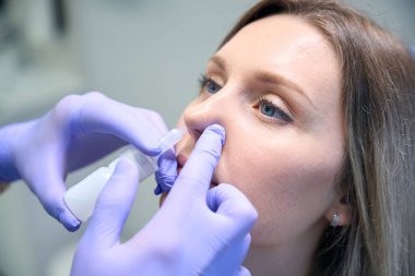 Modern ENT kliniğinde genç bir kadın için burun ameliyatı yapan bir doktor. Burun tıkanıklığı, sinüzit, alerji konsepti.