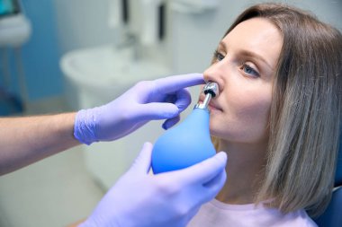 Klinikte genç bir kadın için burun ameliyatı yapan otolaringolojistin kesilmiş fotoğrafı. Burun tıkanıklığı, sinüzit, alerji konsepti.