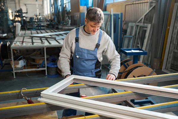 Erkek işçi alüminyum ve PVC pencere üretimi fabrikasında çalışıyor.