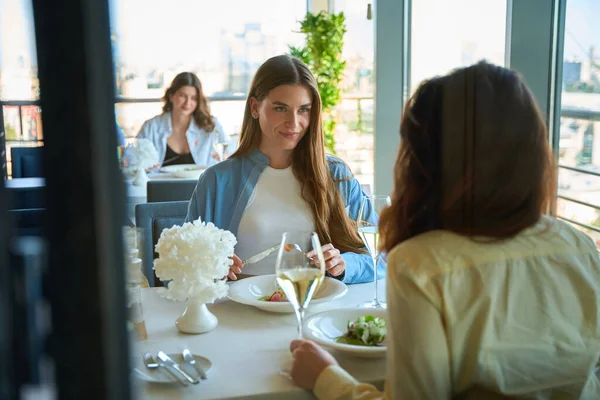 Lokantada bayan arkadaşıyla yemek yiyen mutlu genç bayan.