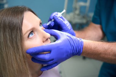 Göz hekimliği kliniğinde kadın hastalara göz iğnesi yapan erkek doktorlara yakın çekim. Tıp, sağlık hizmeti kavramı