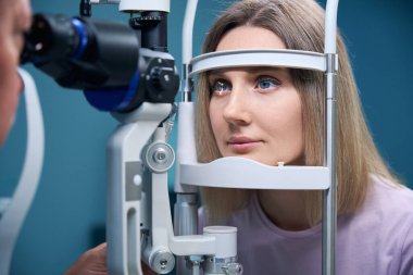 Göz doktoru kliniğinde göz kırılması testi yaptıran genç bir kadın. Tıp, sağlık hizmeti kavramı