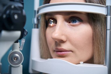 Göz muayenesindeki genç kadın göz doktorlarının muayenehanesinde Iris 'e ışık tutuyor. Tıp, sağlık hizmeti kavramı